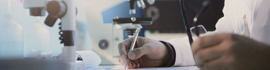 Laboratory scientist at a desk reviewing mold test results beside a microscope.